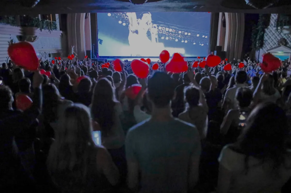 Public dans une salle obscure du Cinéma Karaoké de Lille, agitant des ballons rouges en forme de cœur pendant Bohemian Rhapsody.