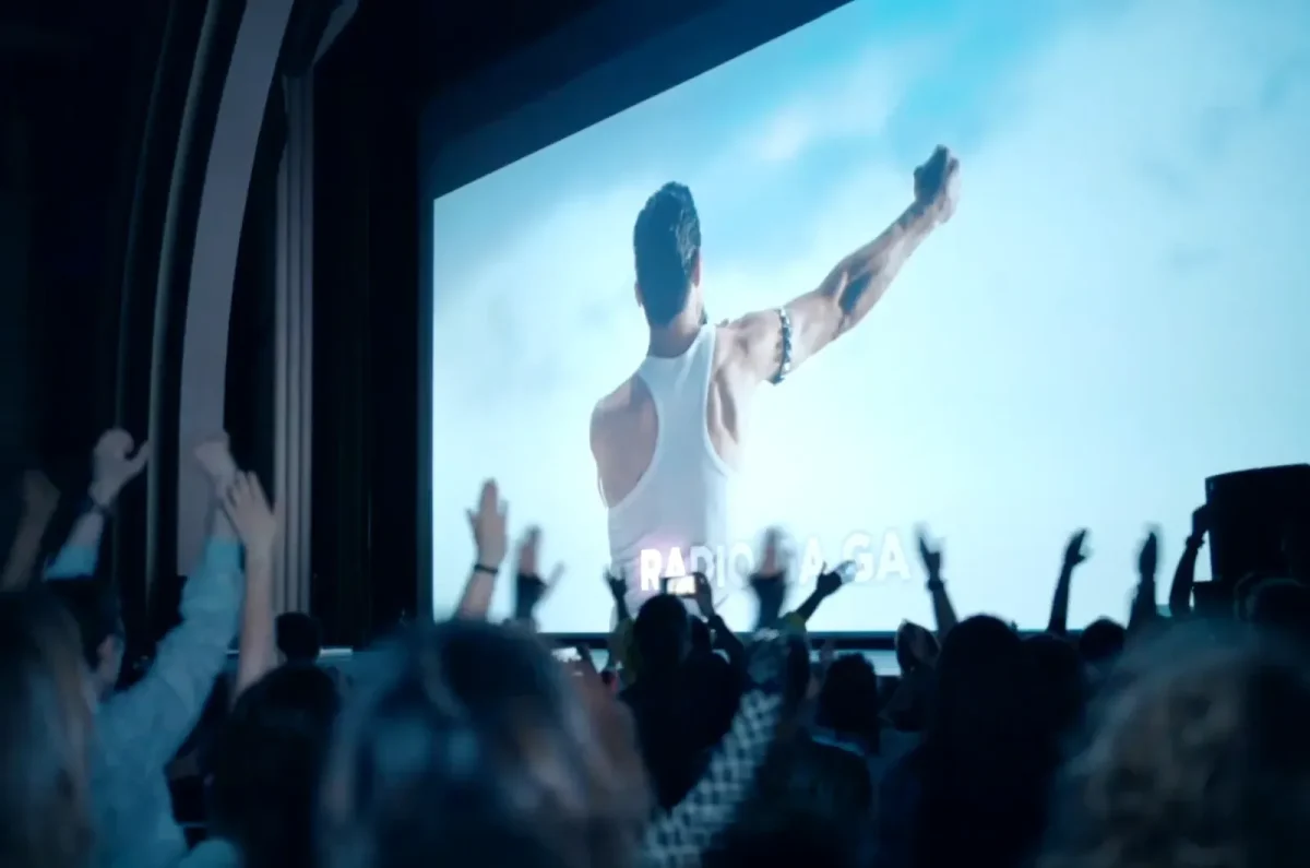 Le public lève les mains devant l'écran du Cinéma Karaoké de Lille, où l'on peut lire "RADIO GAGA.