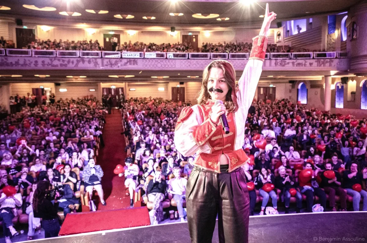 Un artiste en costume et fausse moustache accueille un large public du Cinéma Karaoké à Lille avec "Bohemian Rhapsody".