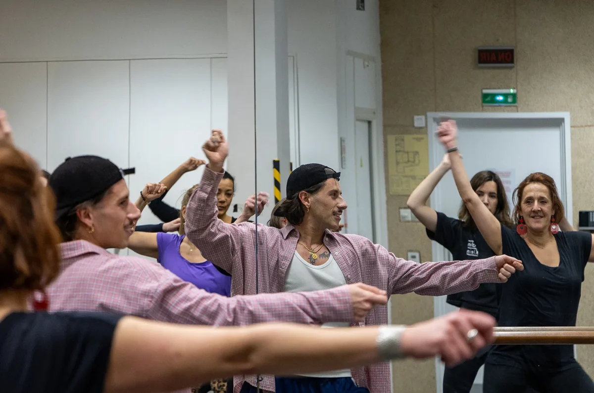 Des personnes se joignent à un cours de danse animé à Paris, debout devant des miroirs, les bras levés, comme s'il s'agissait d'une véritable fête de la danse.